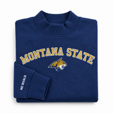 Oversized navy blue Montana State Mock Neck - Navy sweatshirt featuring MONTANA STATE in gold lettering above a bobcat mascot logo, with NO RIVALS printed on the sleeve cuff.