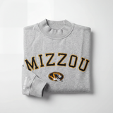 The No Rivals Mizzou Mock Neck is a heavyweight cotton, oversized gray sweatshirt with “MIZZOU” in bold black and gold, the University of Missouri tiger logo beneath, and “NO RIVALS” printed in white on the sleeve.