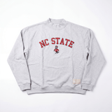The No Rivals NC State Mock Neck is a gray heavyweight cotton crewneck featuring red NC STATE text and a mascot illustration on the front, plus a small beige tag near the bottom hem.