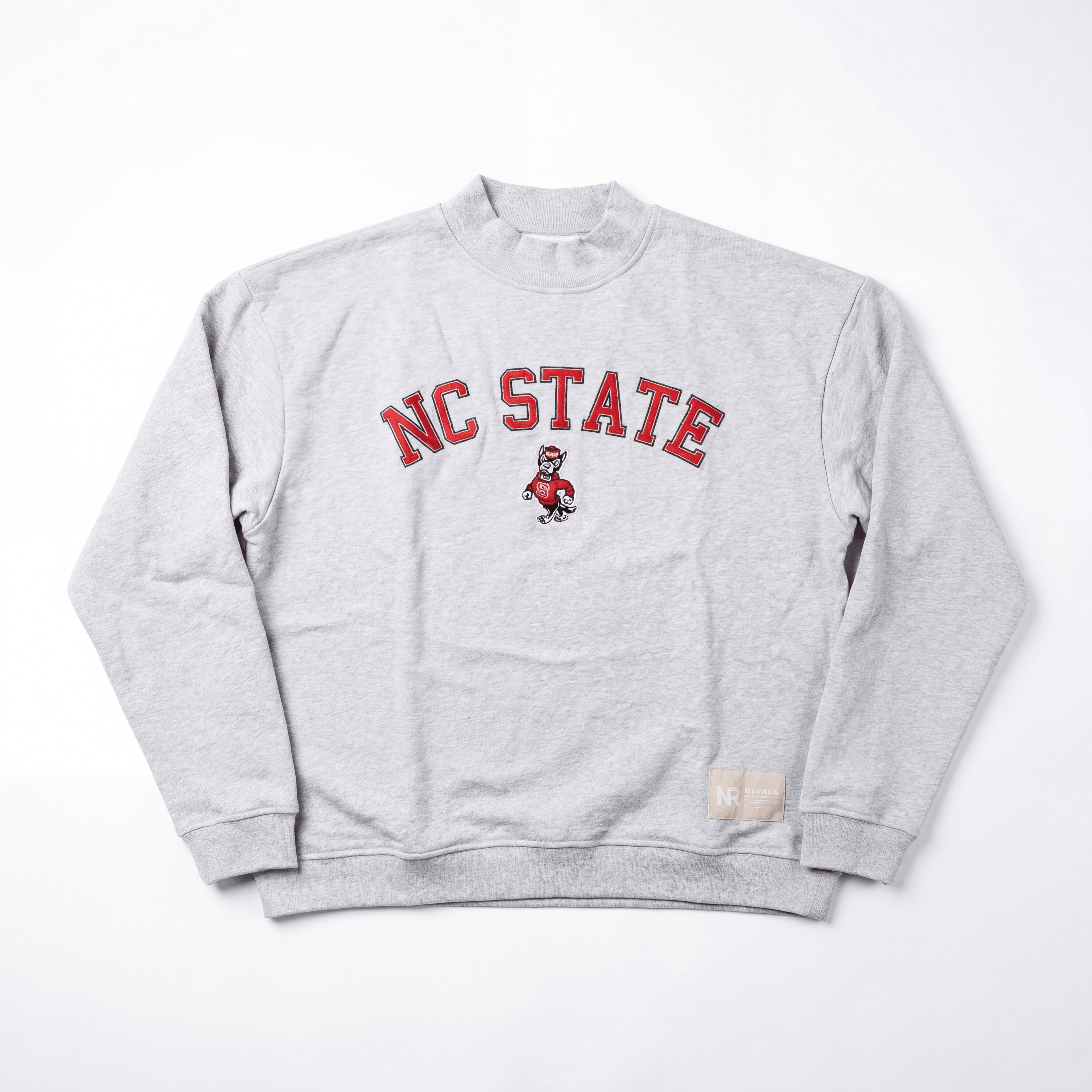 The No Rivals NC State Mock Neck is a gray heavyweight cotton crewneck featuring red NC STATE text and a mascot illustration on the front, plus a small beige tag near the bottom hem.