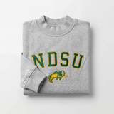The NDSU Mock Neck by No Rivals is a folded gray heavyweight cotton sweatshirt featuring "NDSU" in green and yellow with a bison logo on the front, and "NO RIVALS" printed in white on one sleeve.
