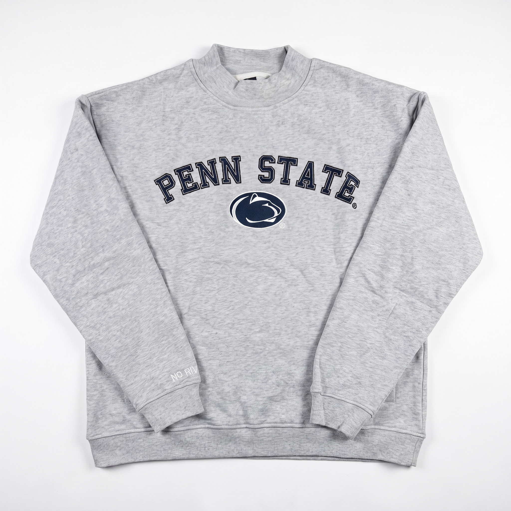 A light gray mock neck sweatshirt by No Rivals, featuring PENN STATE and a navy blue Nittany Lion logo printed on the front. Crafted from heavyweight cotton with a cozy fleece interior, the Penn State Mock Neck is displayed laid flat on a white background.