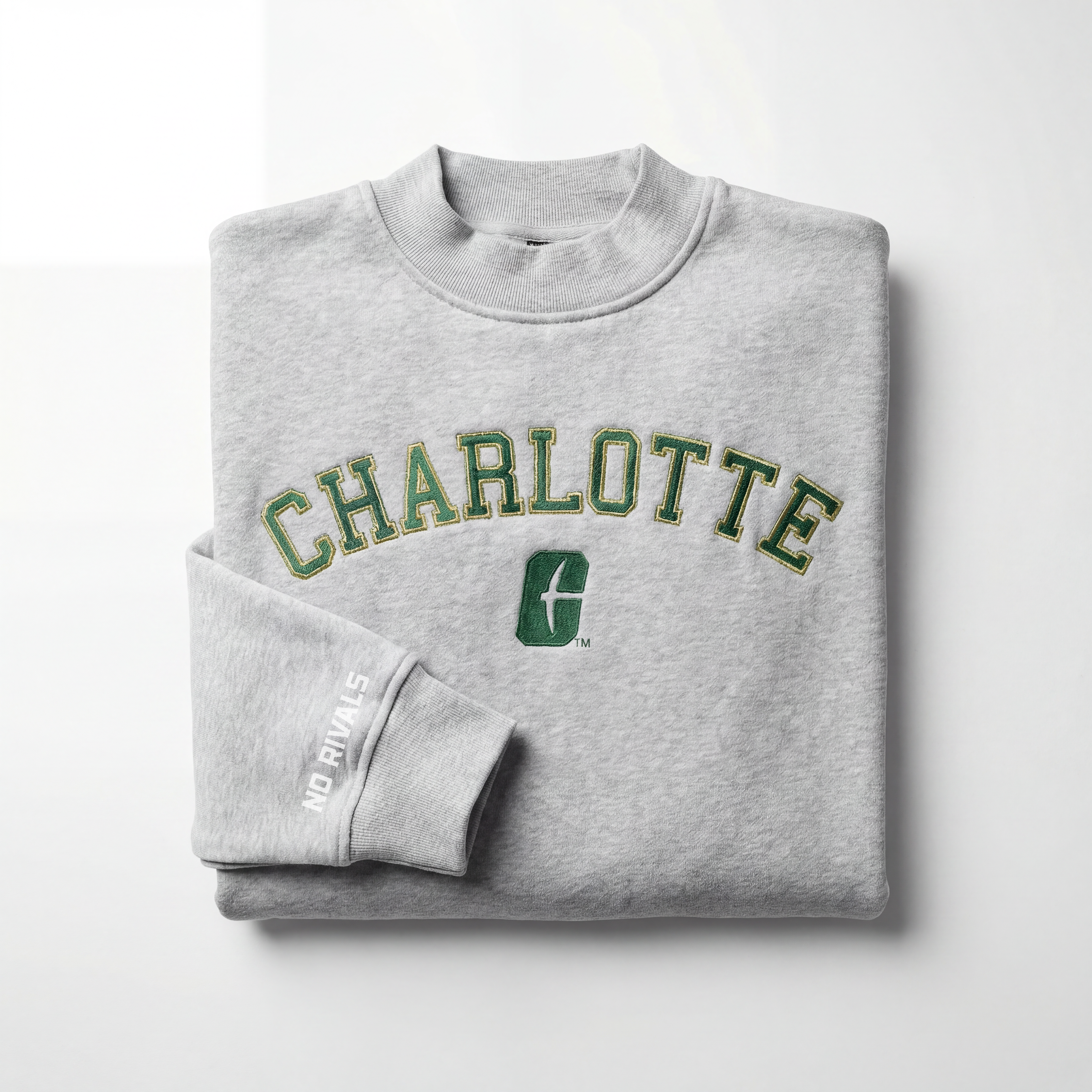 A gray UNCC Mock Neck sweatshirt by No Rivals with "CHARLOTTE" in green and yellow, a green logo underneath, and "NO RIVAL S" on the sleeve. Made from heavyweight cotton and displayed on a plain white surface.