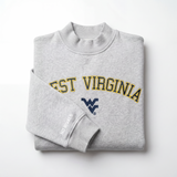 The West Virginia Mock Neck by No Rivals is a heavyweight gray cotton sweatshirt with WEST VIRGINIA in yellow and a blue chest logo, plus "NO RIVALS" in white on the sleeve, shown folded on a white background.