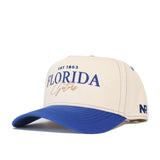 The Florida Vintage Hat is a cream baseball cap with a blue bill, featuring "Florida Gators" and "EST 1853" on the front and "NR" on the side. Made from high quality cotton, this officially licensed snapback is perfect for fans.