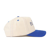 The Florida Vintage Hat is a beige cotton baseball cap with blue stitching, blue eyelets, and a blue brim. Shown from the side, it displays partially visible text on the front panel.