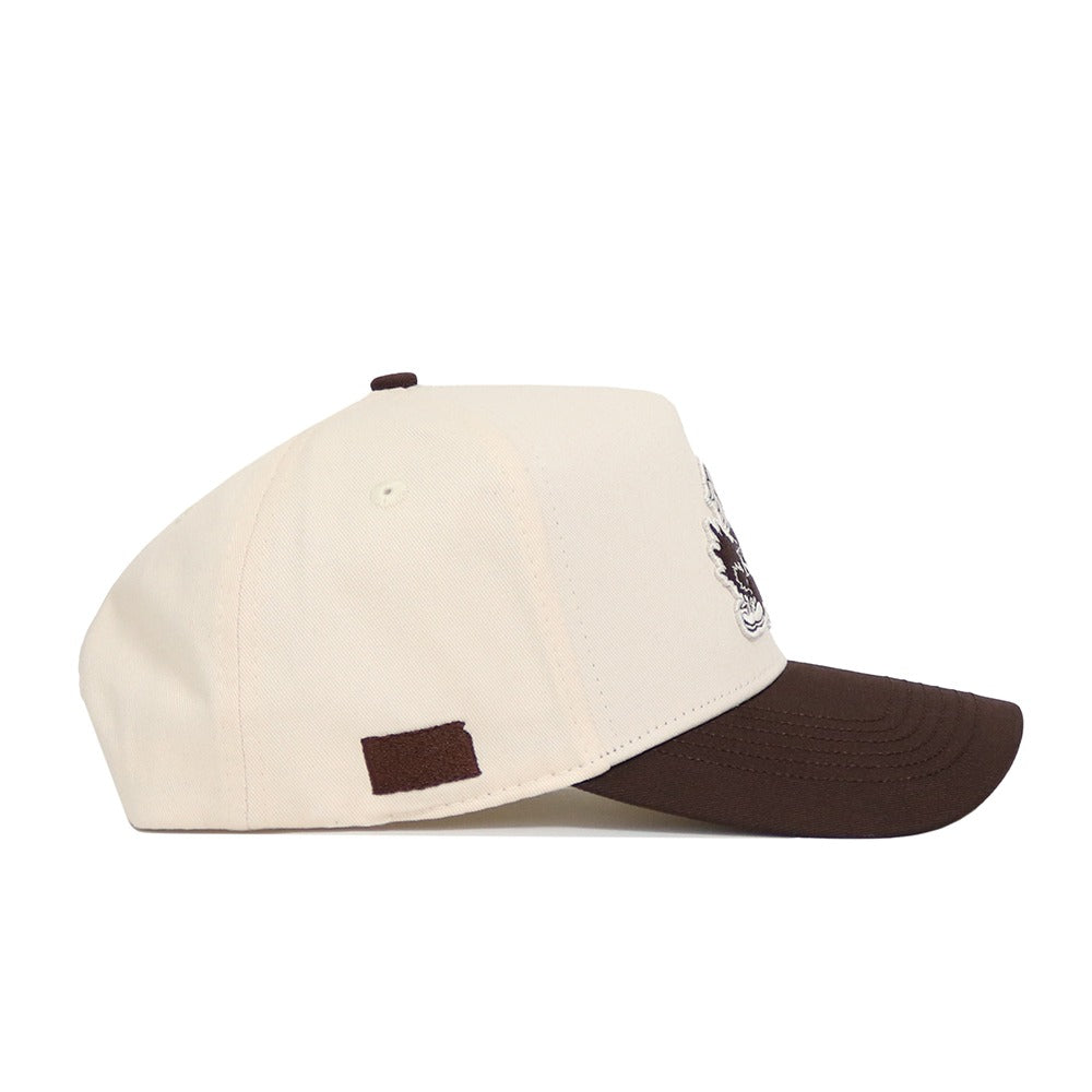 The University of Kansas Espresso Hat by No Rivals is a cream cotton baseball cap with a dark brown brim and a small brown rectangular side patch, shown in left profile.