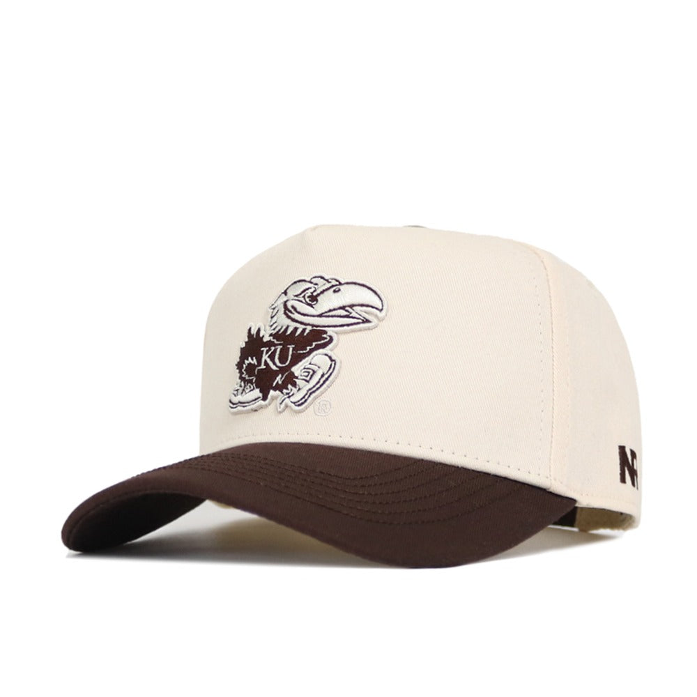 The No Rivals University of Kansas Espresso Hat is a beige snapback with a brown brim, made from quality cotton. It features an embroidered KU Jayhawk logo in brown and white on the front and a small N logo on the side.