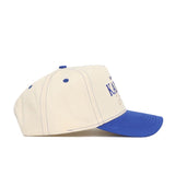 The No Rivals University of Kansas Vintage Hat features a cream color, blue brim, blue stitching, and partial blue side text. Made from high quality cotton with a snapback closure, it's shown in a left side profile view.