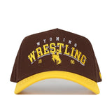The No Rivals Wyoming Wrestling Hat - Takedown Collection is a brown and yellow cotton dad hat with "Wyoming Wrestling 1886" and a bucking horse logo embroidered on the front.