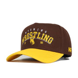 The Wyoming Wrestling Hat - Takedown Collection by No Rivals features brown and yellow cotton, an embroidered cowboy graphic with "Wyoming Wrestling 1886" on the front, NR on the side, and a classic snapback closure.