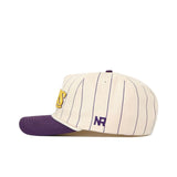 The JMU Vintage Wordmark Hat by No Rivals is a cream cotton baseball cap with navy pinstripes, a purple brim, yellow embroidered front letters, "NR" stitched on the side, and an adjustable snapback for a comfortable fit. Shown from the side.