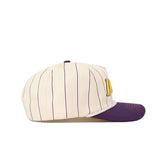 The No Rivals JMU Vintage Wordmark Hat - Pinstripe features a cream base with blue pinstripes, a purple brim, and a yellow embroidered letter on the side. Made of quality cotton with a snapback closure for adjustable fit. Shown in side profile.