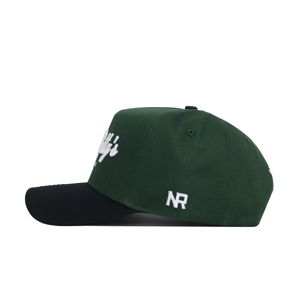 The No Rivals St.Pattys Shamrock Hat is a dark green corduroy cap with a black brim, white embroidered front and side text, unstructured fit, and "NR" stitched on the side panel.