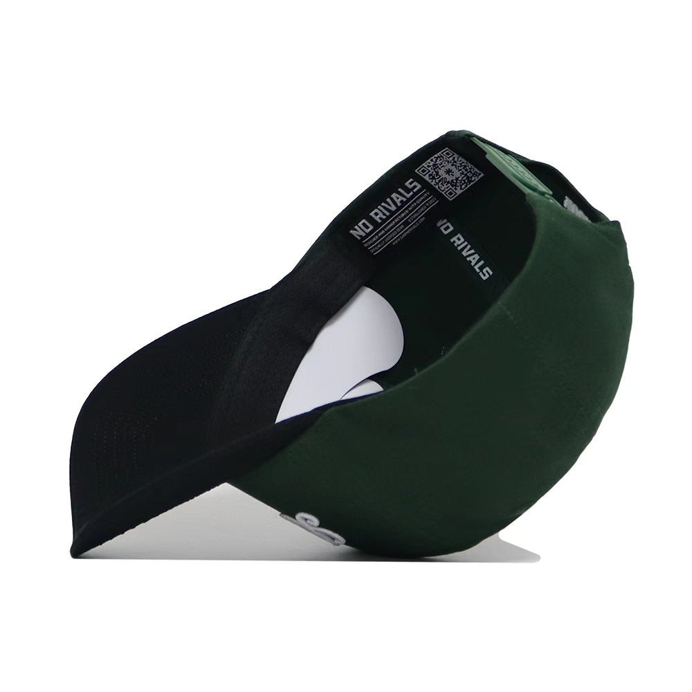 The St.Pattys Shamrock Hat by No Rivals is a green corduroy, unstructured fit cap. Turned upside down, it reveals a black interior with “NO RIVALS” in white and a QR code on the inner band. The brim’s underside is dark.
