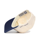 The image shows the Penn State Hockey Hat by No Rivals, beige and navy blue, turned upside down to reveal interior labels—NO RIVALS, ROCKETBYVALLEY—and a QR code on the adjustable inner band.