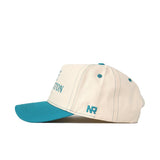 The No Rivals UNC Wilmington Vintage Hat is a cream-colored snapback made of high-quality cotton, with teal brim, stitching, top button, and eyelets. "NR" is embroidered in teal on the side.