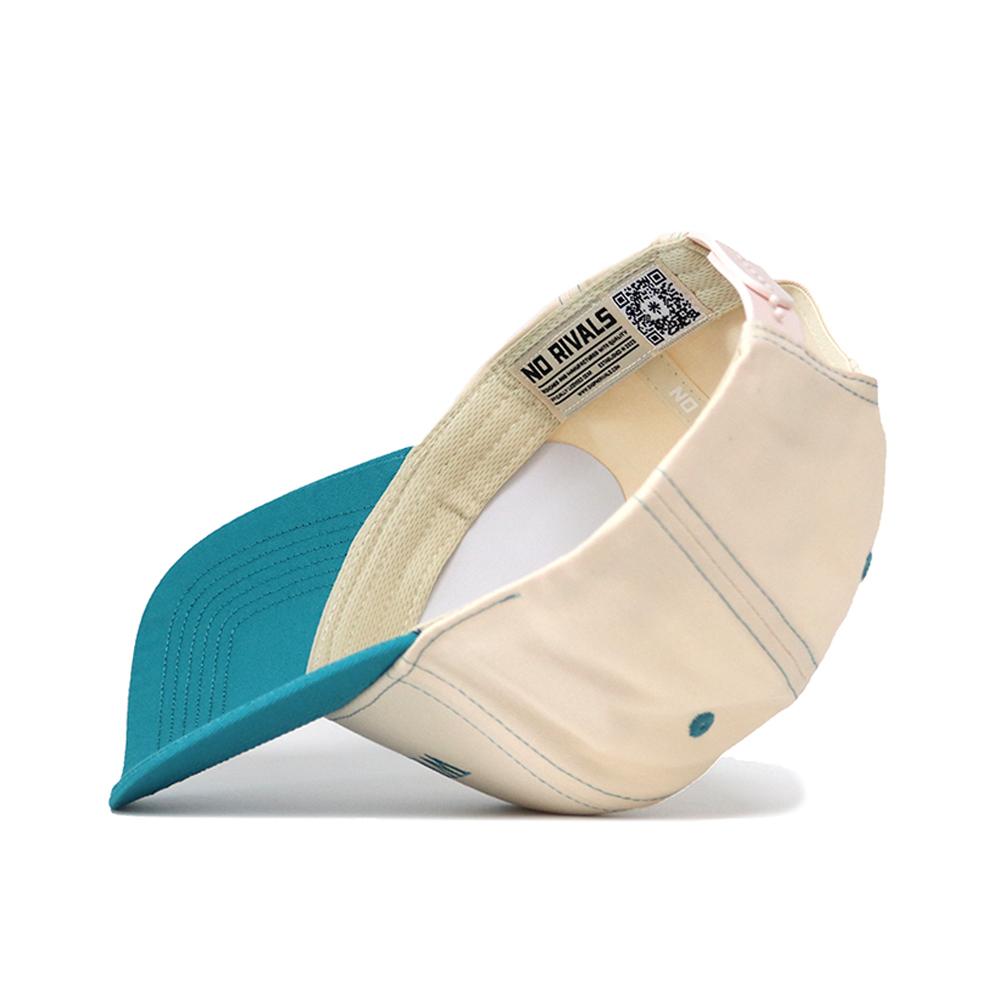 The UNC Wilmington Vintage Hat by No Rivals features a teal brim, beige crown, and inside label with "NO RIVALS" and a QR code. Made from high quality cotton for comfort and durability; shown here upside down to display the interior details.