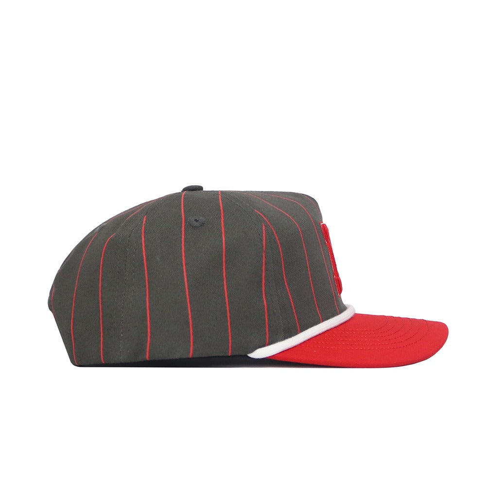 The Nebraska Gray Unstructured Hat by No Rivals features a dark gray design with thin red pinstripes, a red flat brim, and white trim above the brim. Made from high-quality cotton, it’s shown in a side profile on a white background.
