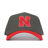 The Nebraska Gray Structured Hat by No Rivals features a grey crown, red brim, and a large red N outlined in white embroidered on the front. Made from high-quality cotton for a comfortable, structured fit.