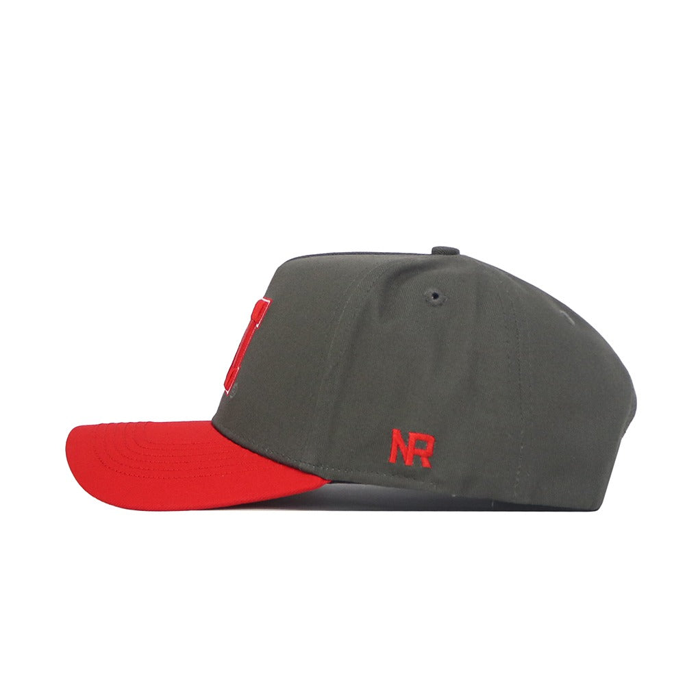 A side view of the No Rivals Nebraska Gray Structured Hat, featuring a snap back, gray crown, red brim, and red "NR" embroidery on the side. Made from high quality cotton for a structured fit.