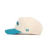 The Upside Down Seahawks Hat - UNCW by No Rivals features classic colors with a cream cotton build, teal blue brim, NR teal embroidery on the side, and partially visible blue lettering on the structured front.