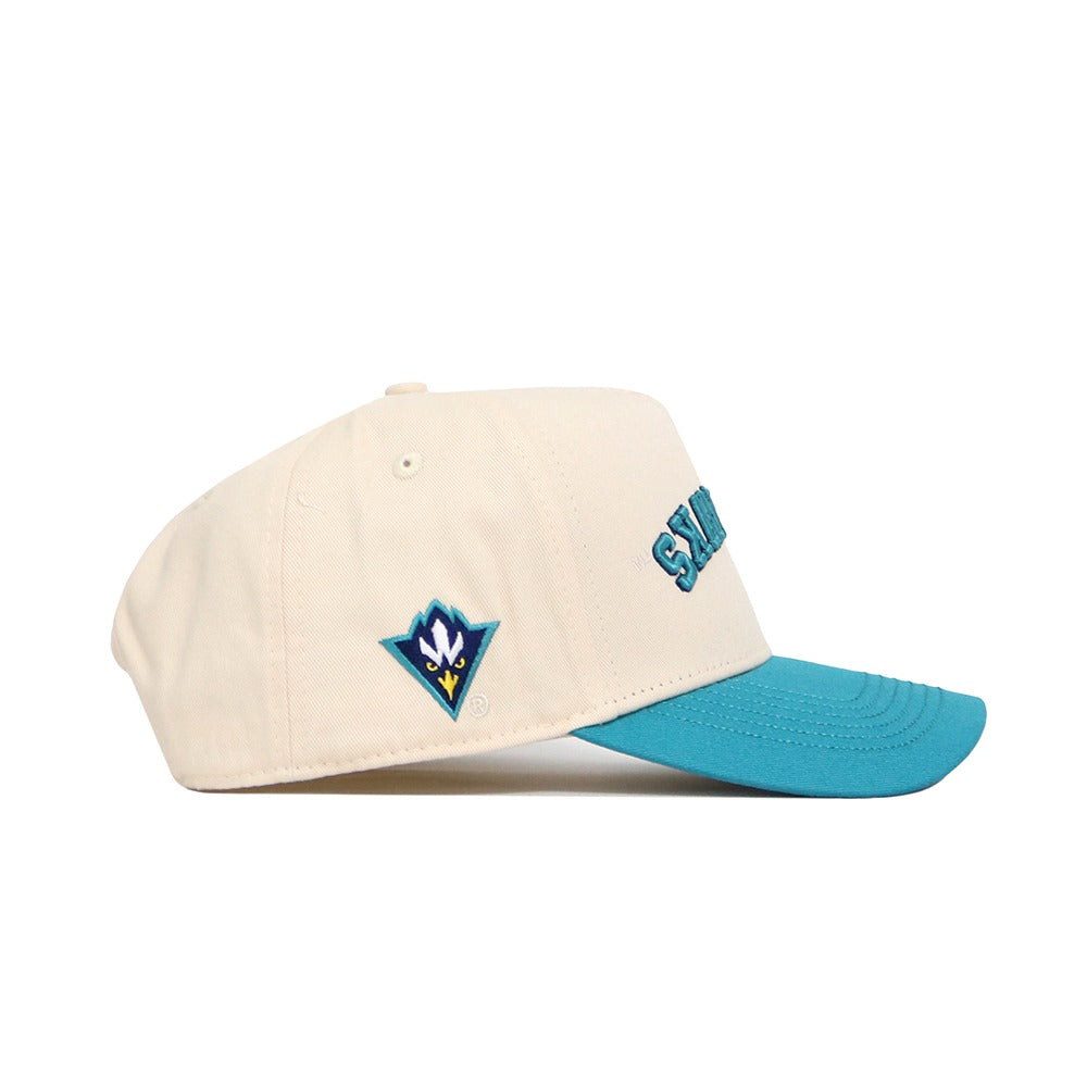 Side view of the Upside Down Seahawks Hat - UNCW - Classic Colors by No Rivals: cream-colored with a teal brim, embroidered front letters, a colorful bird logo on the side, and a structured snapback design in high-quality cotton.