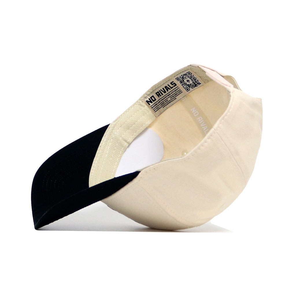 The OSU Bear Hat by No Rivals is shown upside down, displaying its cream color, black brim, inside label with the No Rivals brand name, and a QR code near the inner band.