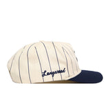 The Longwood Pinstripe Hat by No Rivals features a cream base with thin navy stripes, a navy visor, an embroidered Longwood logo in navy, and a snapback closure for an adjustable fit.