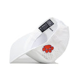 The Clemson Golf Hat - Swinging - White by No Rivals is shown lying on its side, with an embroidered orange paw print logo on the front, a perforated back for breathability, and an interior tag featuring “NO RIVALS” text and a QR code. Designed for your gameday fit, this cap also has a snapback closure for a customized fit.
