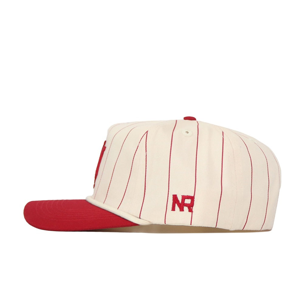 The Indiana University Pinstripe Hat by No Rivals features a cream base with red pinstripes, a red brim, and the “NR” logo embroidered in red on the side. This unstructured cap has a snapback closure for an adjustable fit and is displayed from the side against a plain white background.