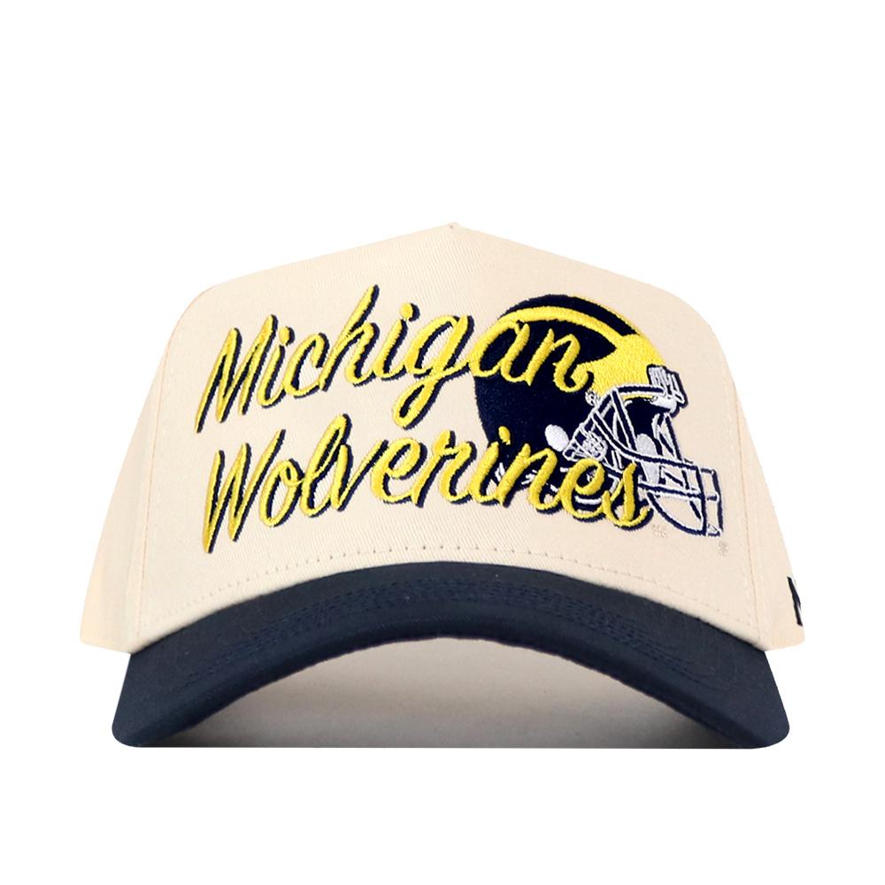 The No Rivals Michigan Wolverines Script Overlay Hat is a beige and navy blue snapback featuring an officially licensed embroidered logo and a football helmet graphic on the front.