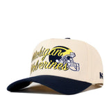 Show off your team pride with the No Rivals Michigan Wolverines Script Overlay Hat, a beige snapback cap with a black brim. This officially licensed hat features bold Michigan Wolverines text, a football helmet graphic, and an embroidered yellow wolverine logo on the front—making it the perfect choice for any fan.