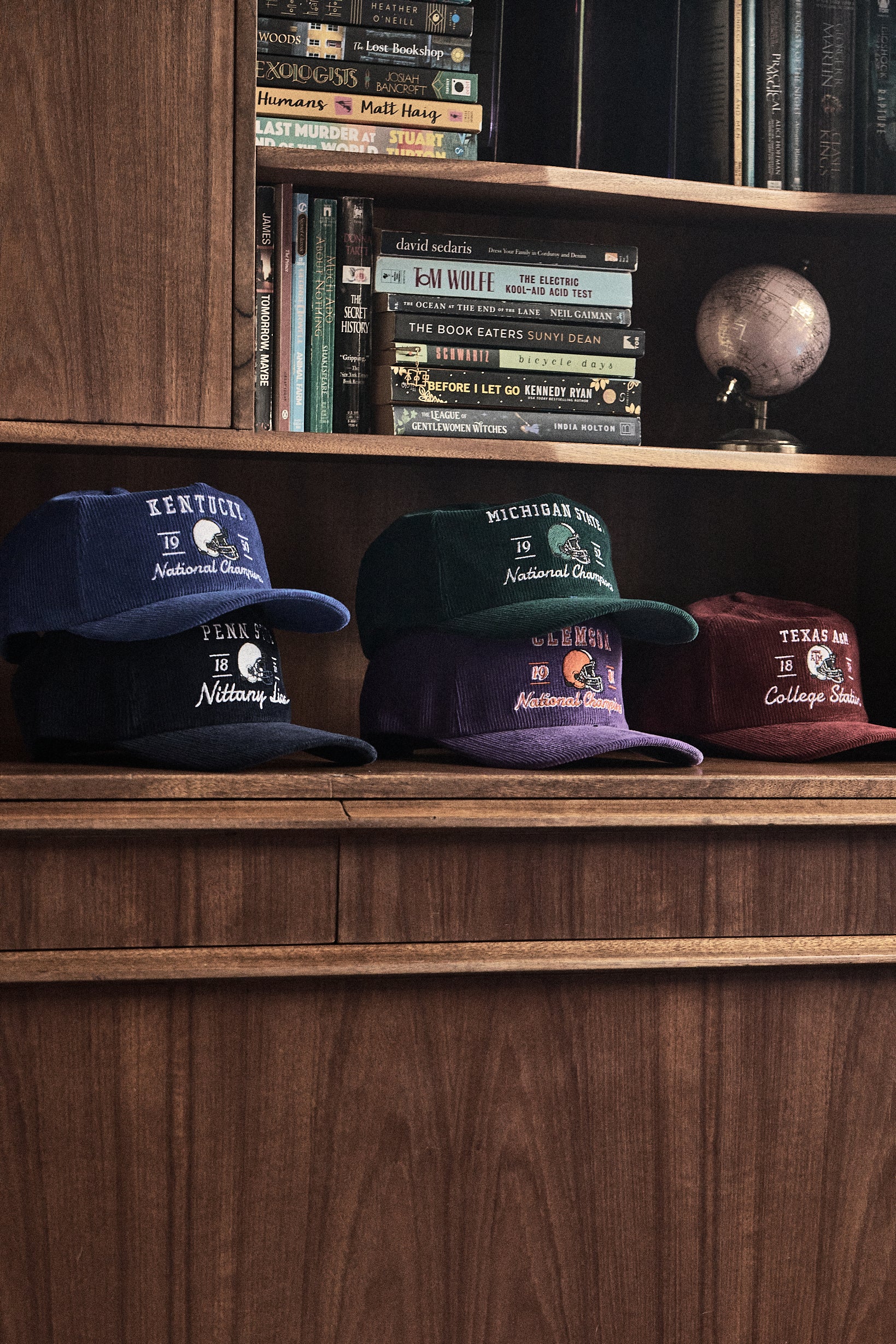 Vintage Cord hats on display. 5 hats sitting on bookshelf.